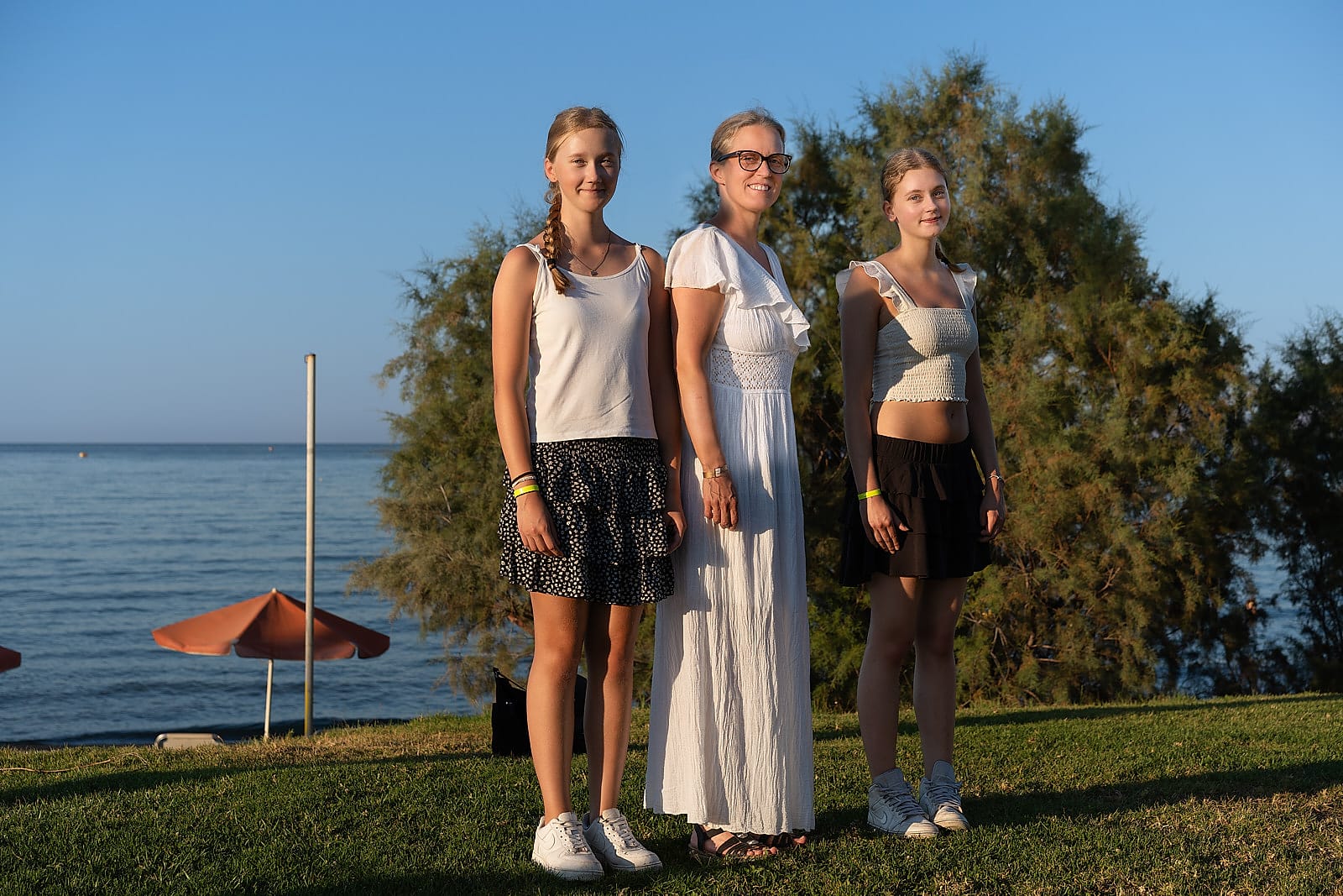 Mother and two daughters standing on the grass overlooking the sea at Agia Marina