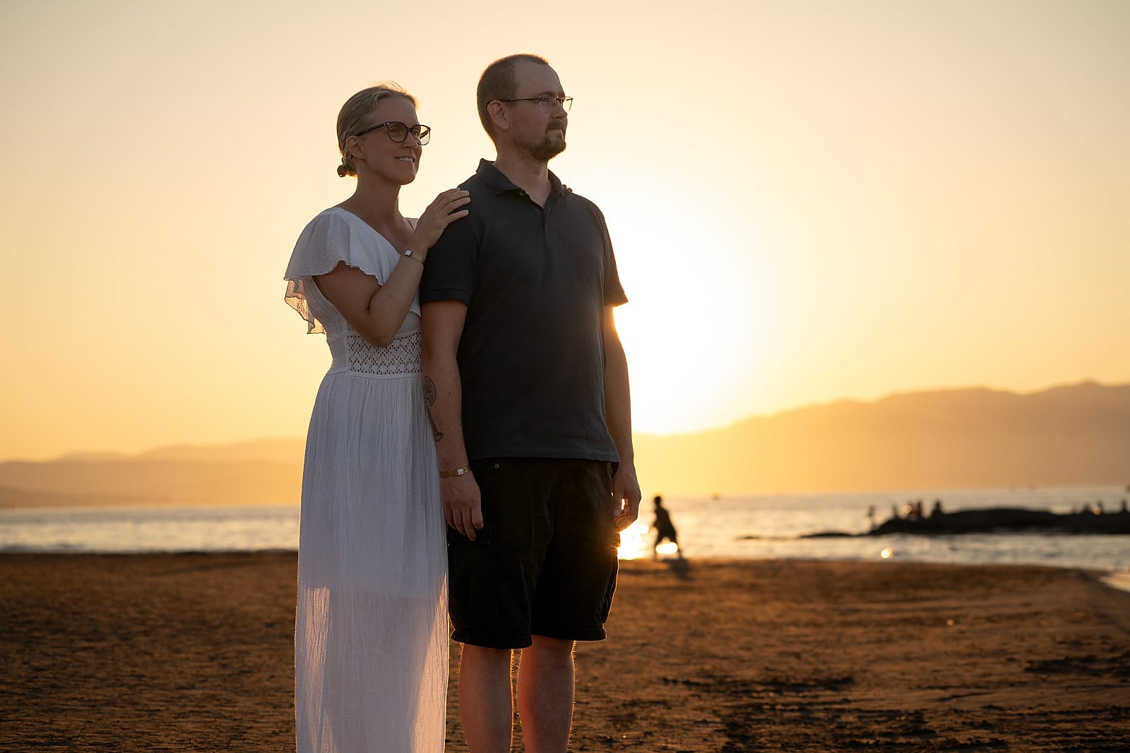 Couple standing together on Agia Marina beach in warm sunset colour