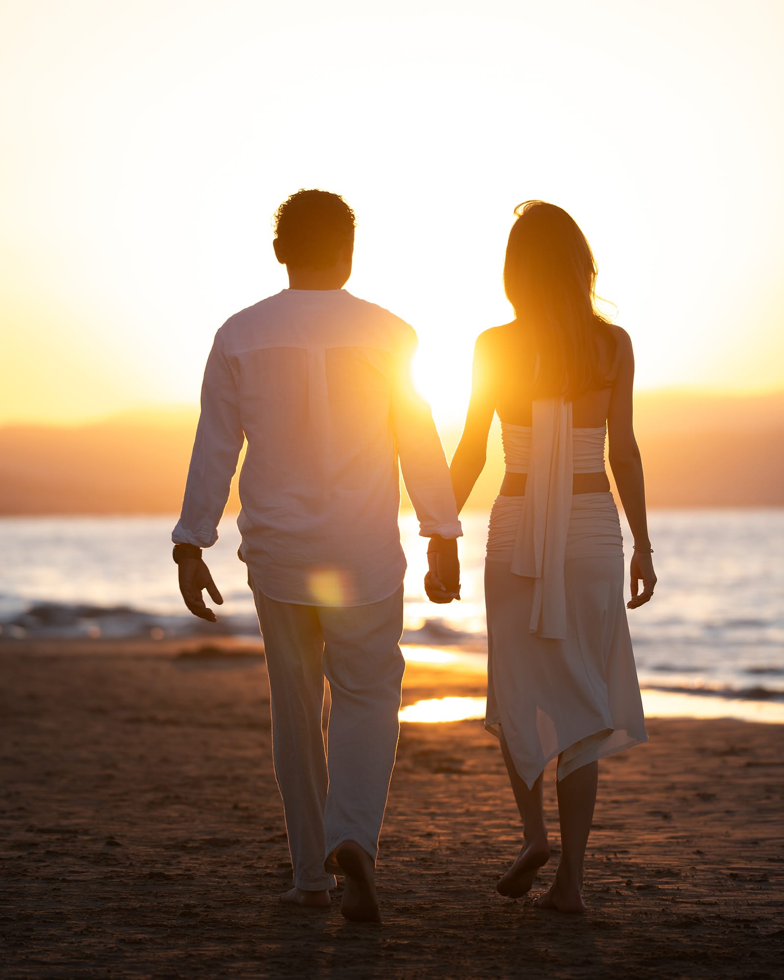 Couple walking hand in hand into the sunset on Agia Marina beach